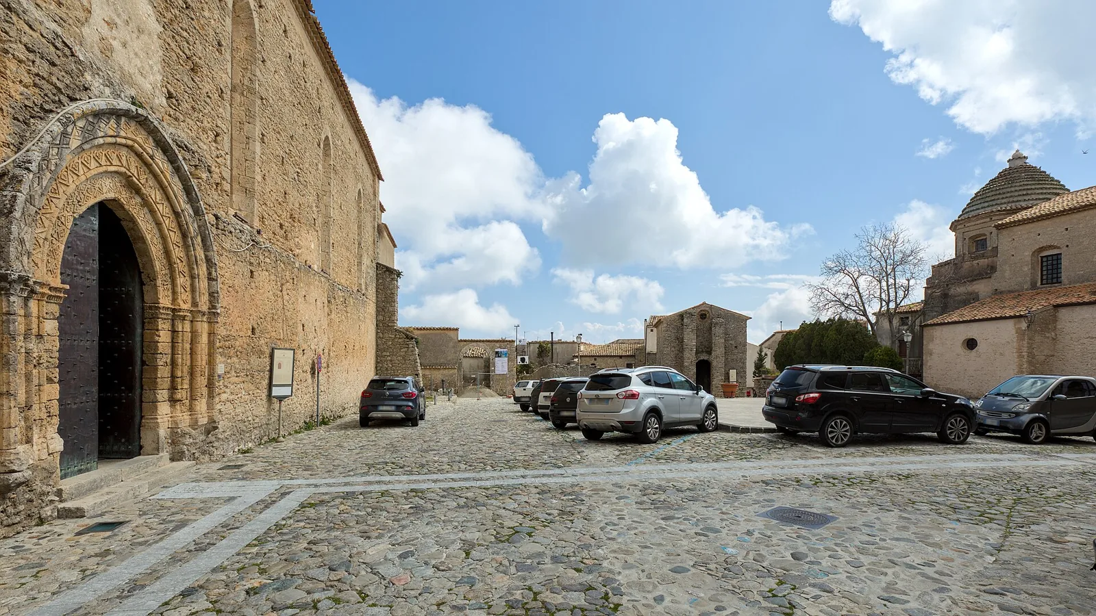 Tre Chiese Square in Gerace with cobbles and cars