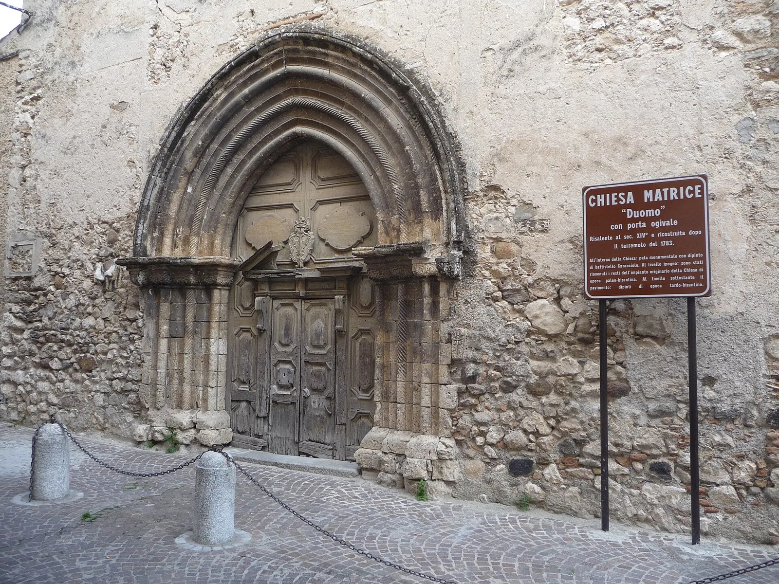 Gothic portal of Stilo Duomo with information sign.